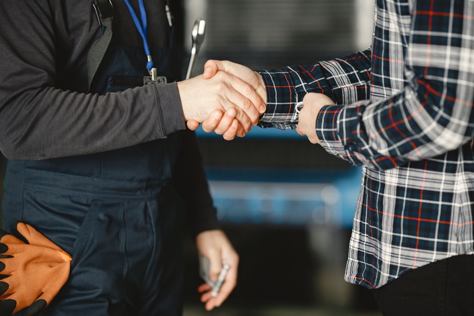 Close-up of a handshake between workers in a workshop, symbolizing business agreement and teamwork.