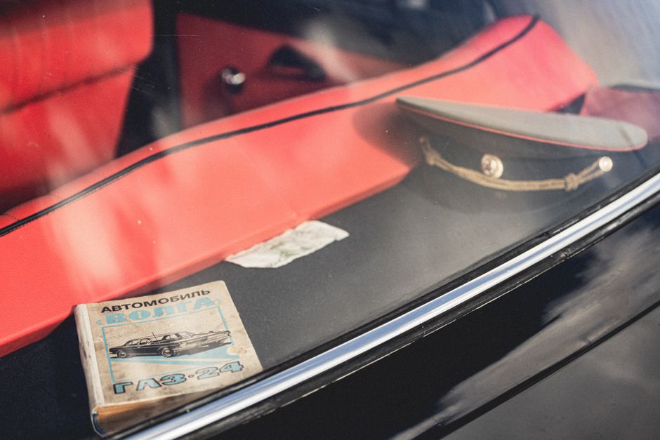 A nostalgic view of a vintage Soviet car interior, showcasing a uniform cap and a Volga manual.